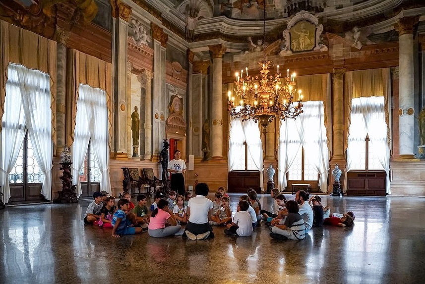 Bambini seduti per terra in una sala museale